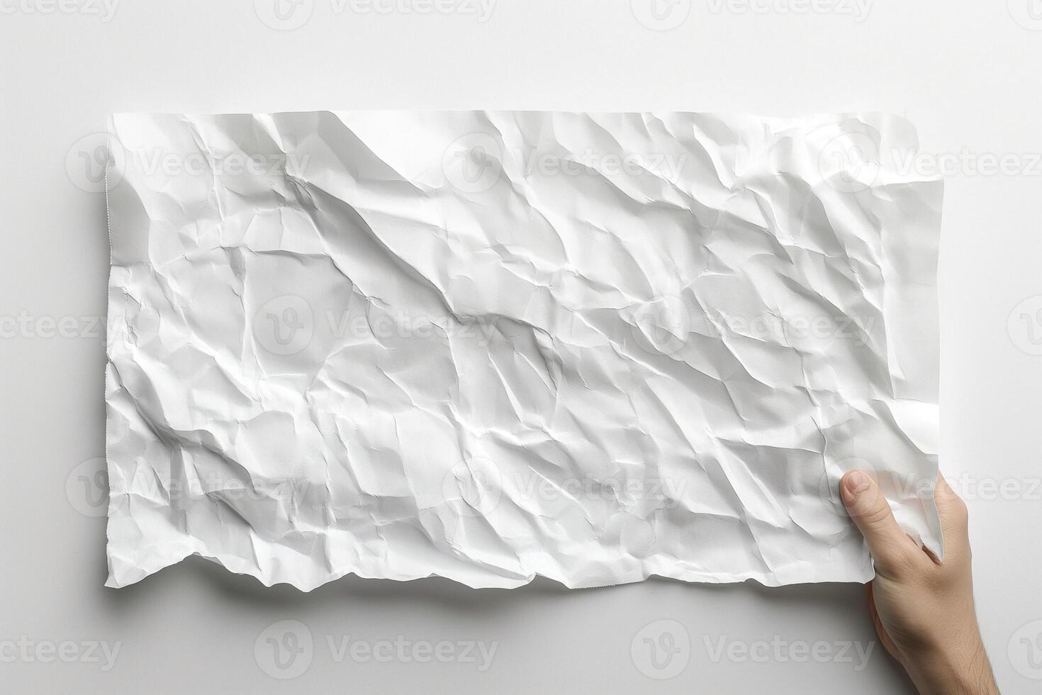 A hand holds a crumpled sheet of white paper against a clean, minimalistic background. photo