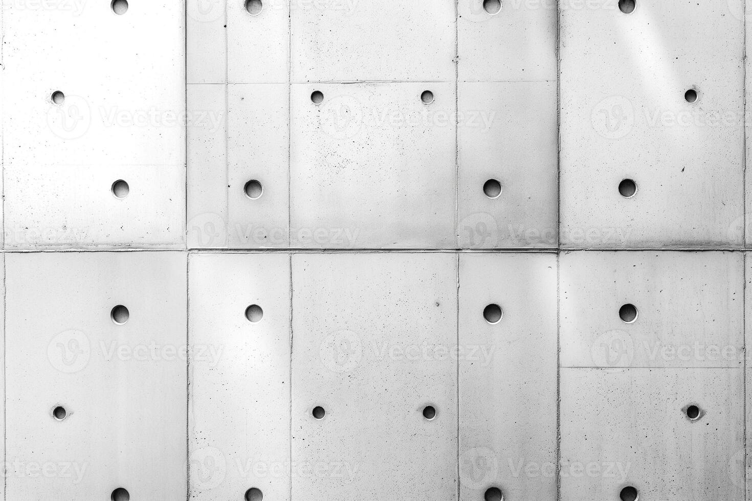 Abstract monochrome concrete wall with circular holes creating a unique visual texture. photo