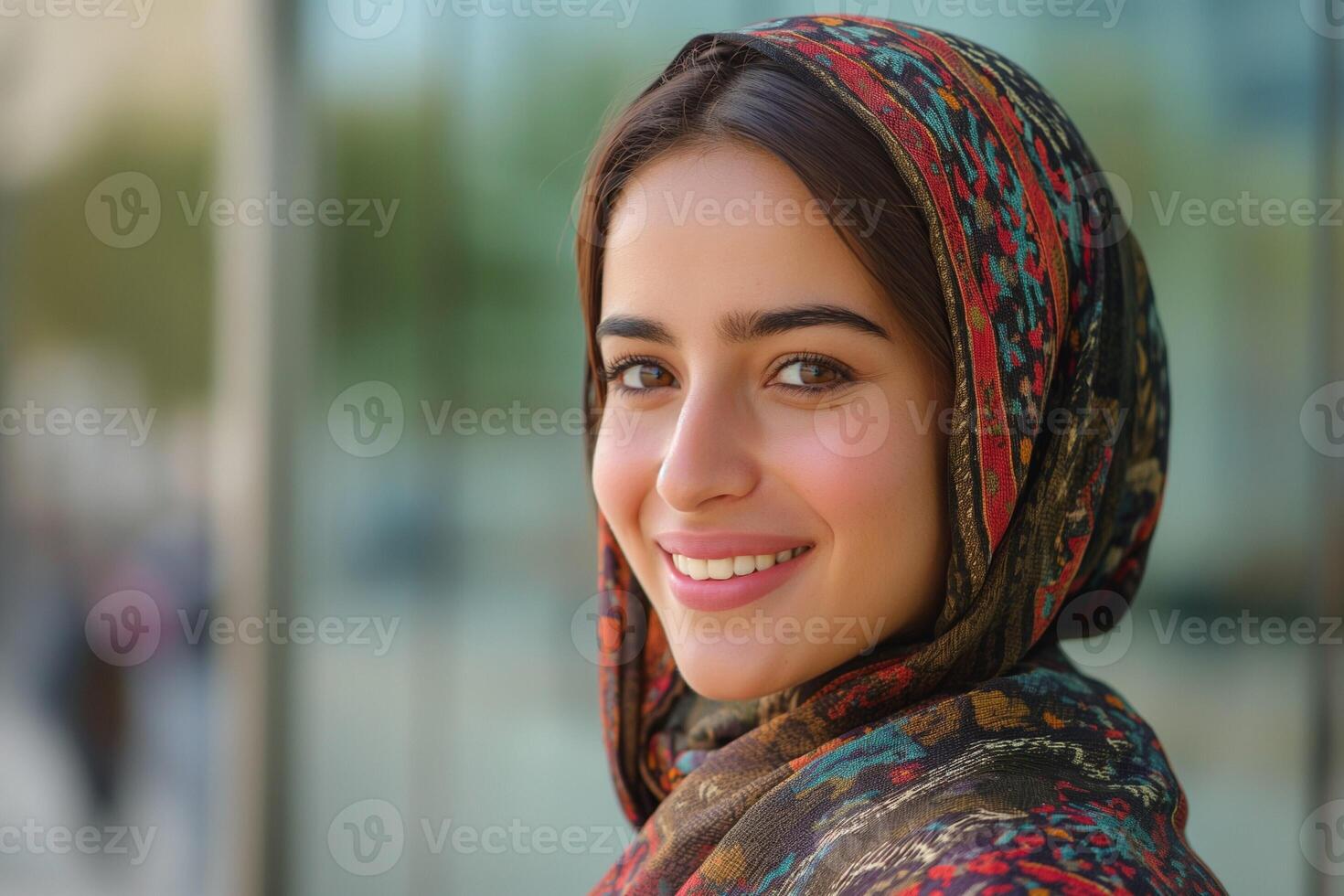 Smiling young woman in a colorful headscarf, exuding warmth and positivity in an outdoor setting. photo