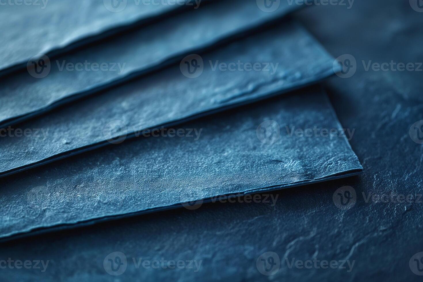 Close-up of layered dark blue textured paper sheets creating a moody and artistic composition. photo