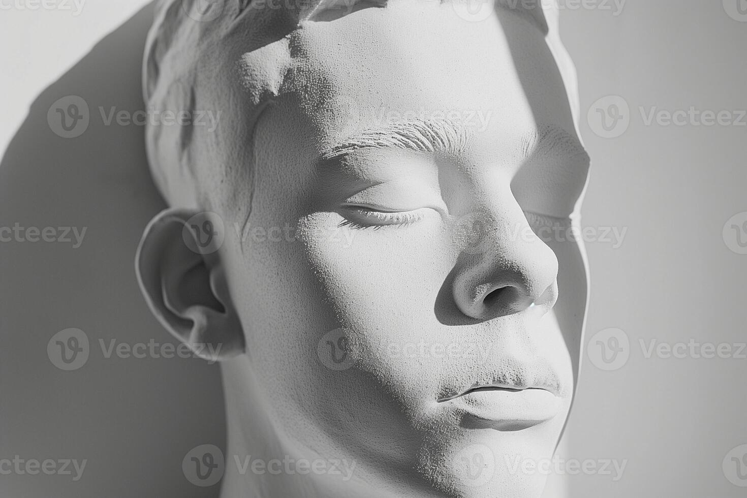 A serene close-up of a life-like white sculpture of a male figure with closed eyes, exuding calmness and tranquility. photo