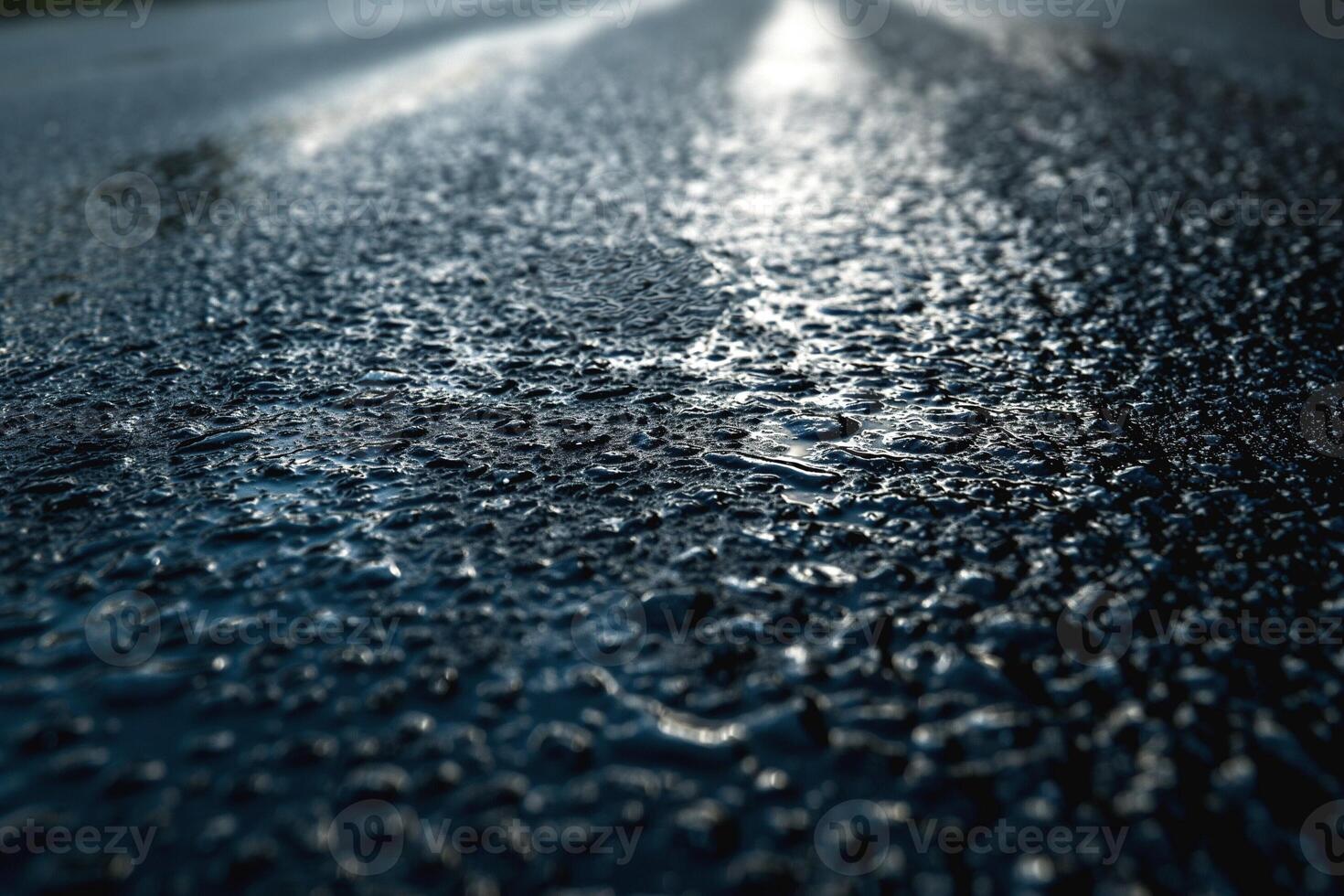 Close-up of glistening water droplets on a dark asphalt road, creating a serene and reflective mood. photo