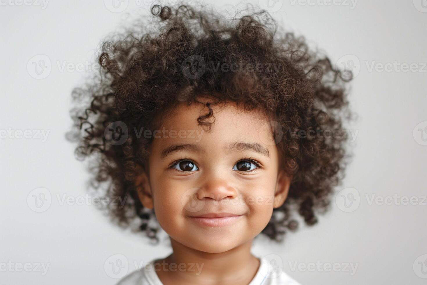 A joyful young Black boy with curly hair beams at the camera, showcasing his infectious smile. photo