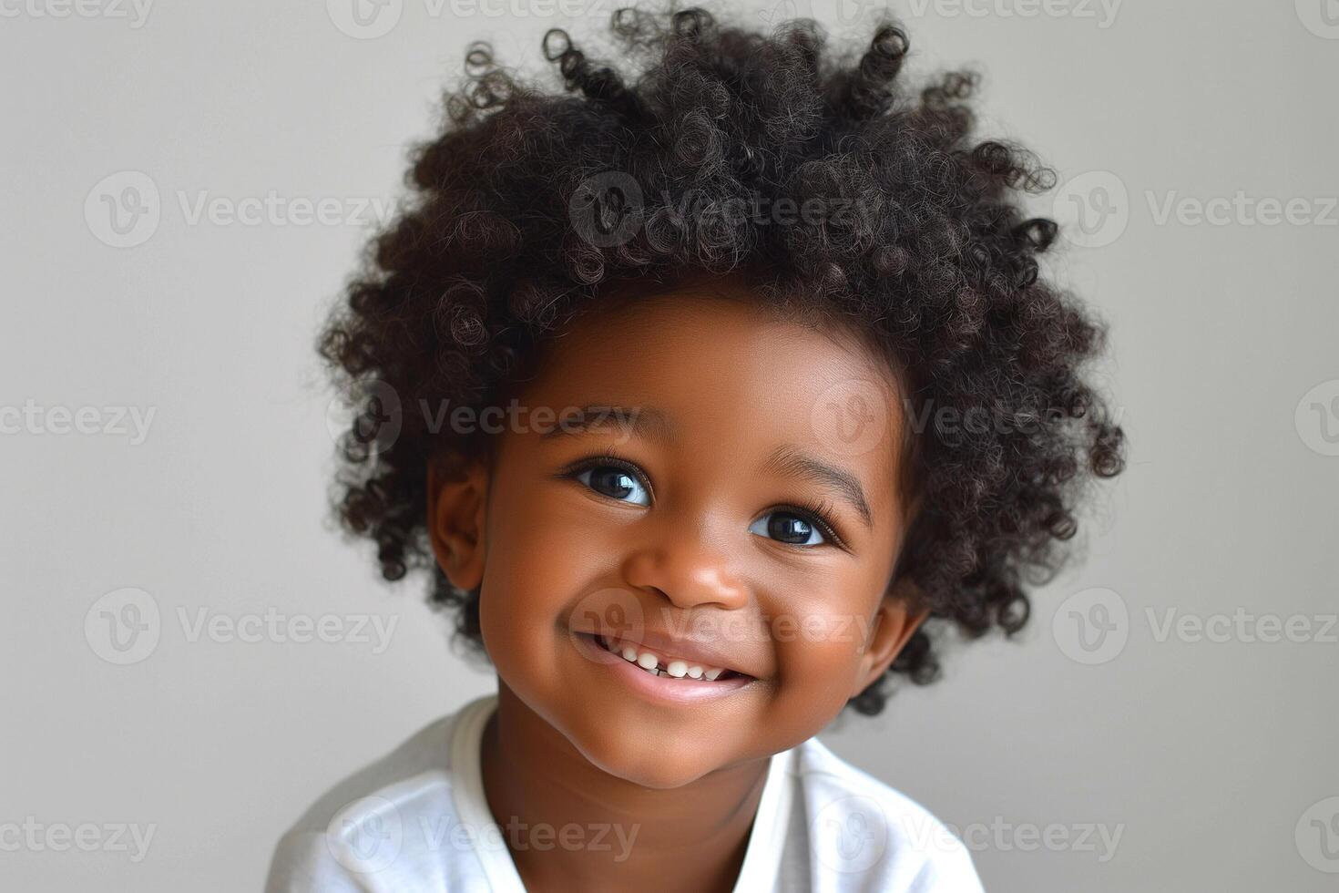 A joyful young Black boy with curly hair beams with happiness, showcasing his bright blue eyes and charming smile. photo