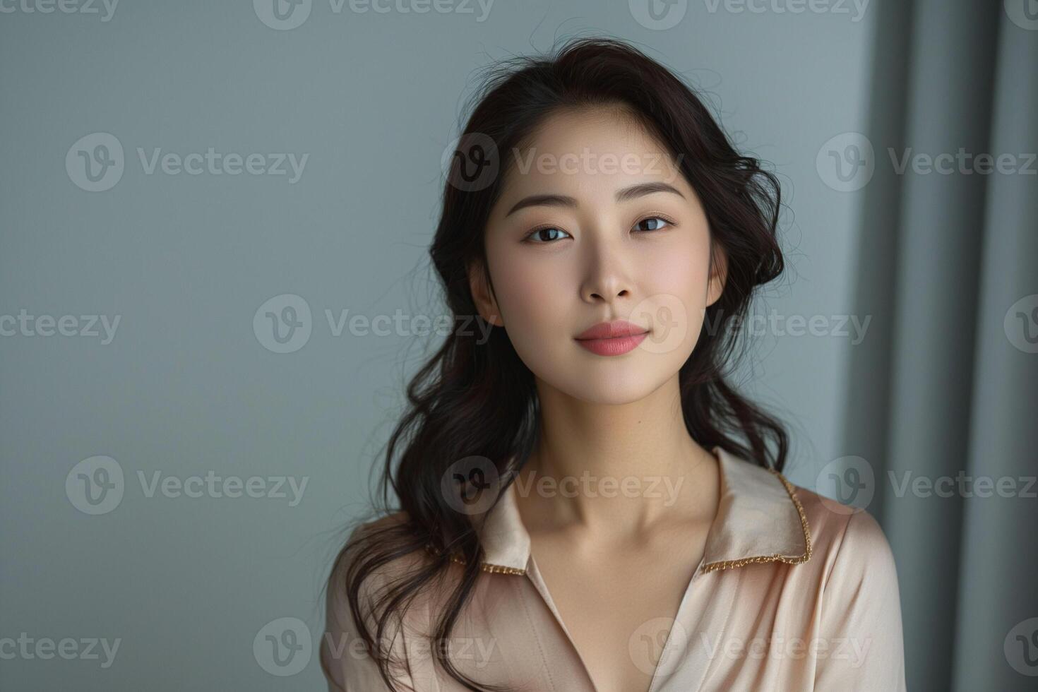 A young Asian woman with long, wavy hair poses gracefully, exuding confidence in a soft, elegant setting. photo