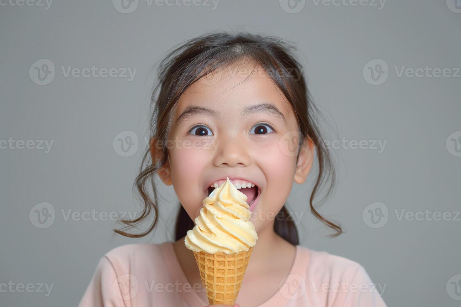 Excited young Asian girl enjoying a sweet cone of ice cream with a joyful expression. photo