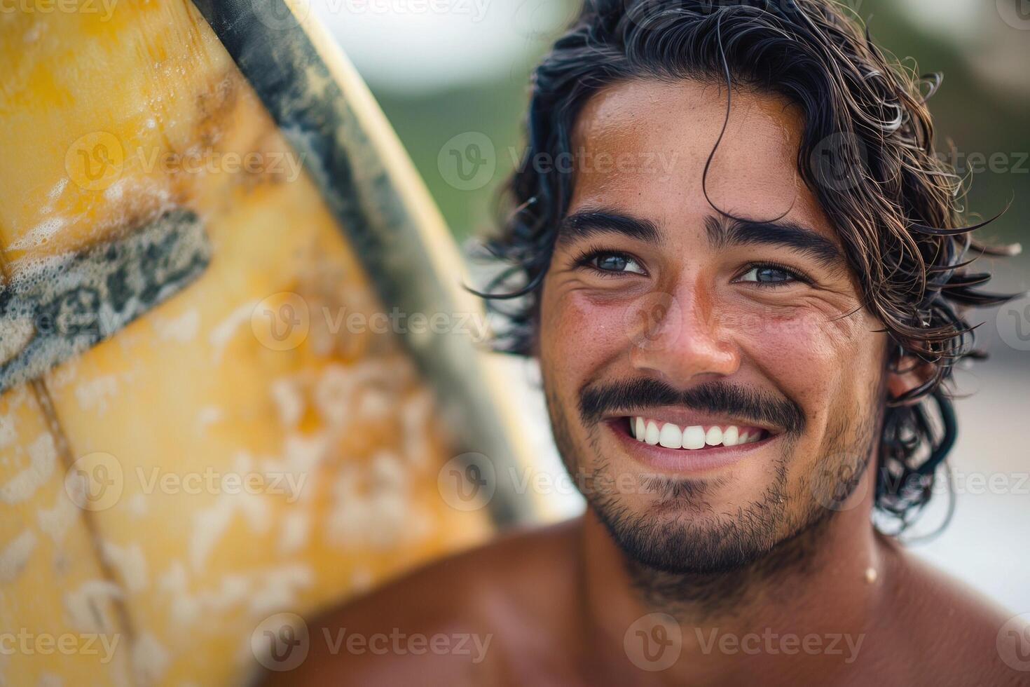 Smiling young male surfer with tan skin and long hair, enjoying a sunny day at the beach. photo