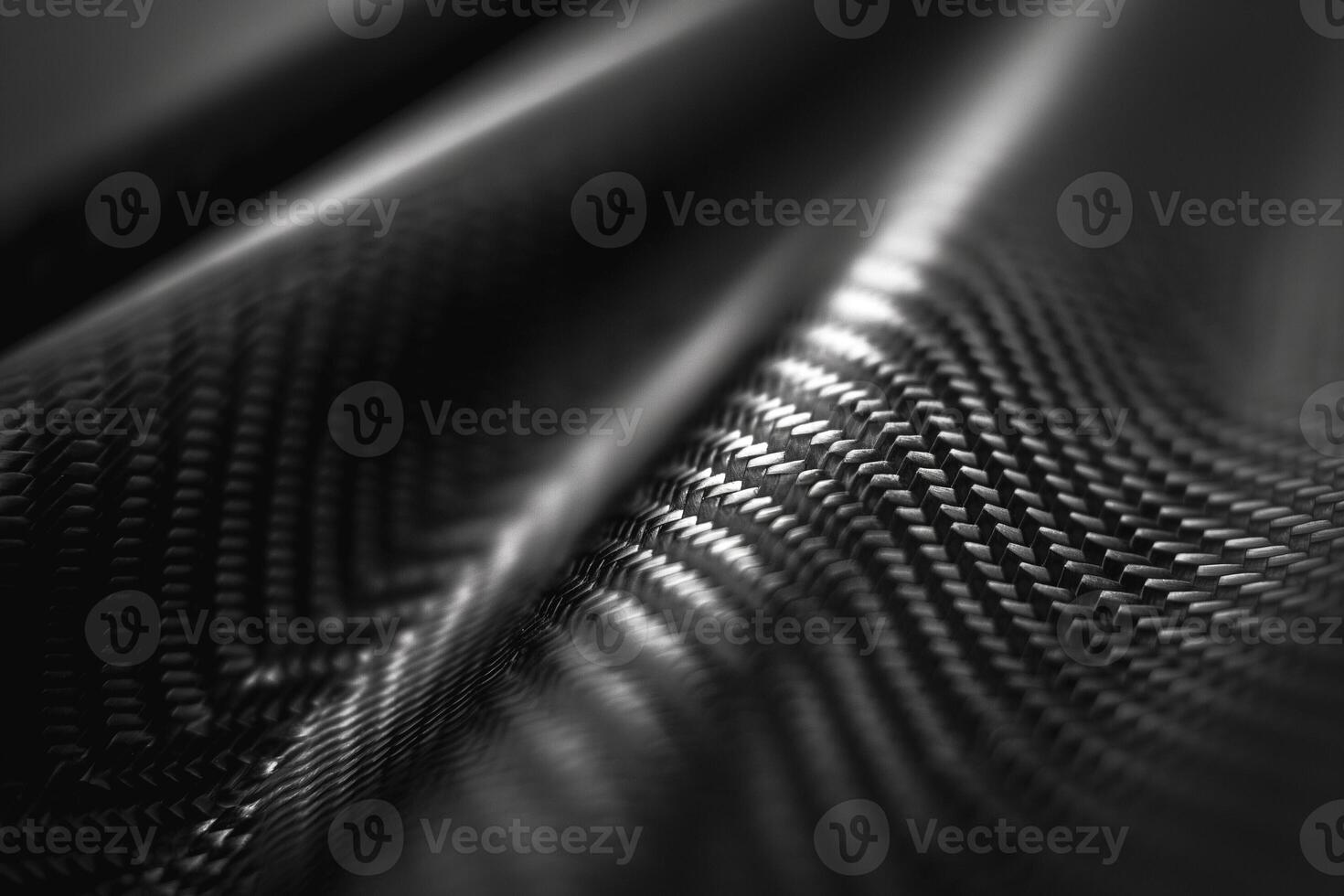 Abstract close-up of textured black carbon fiber material with dynamic patterns and reflections. photo