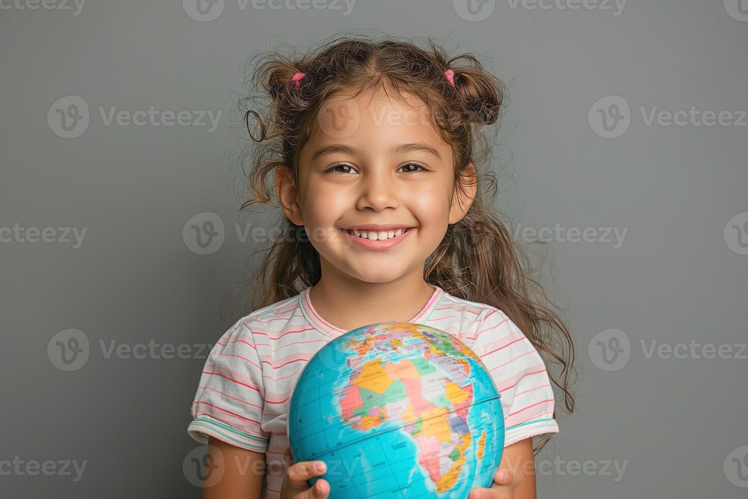 Cheerful young Latina girl holding a globe, showcasing her enthusiasm for the world around her. photo