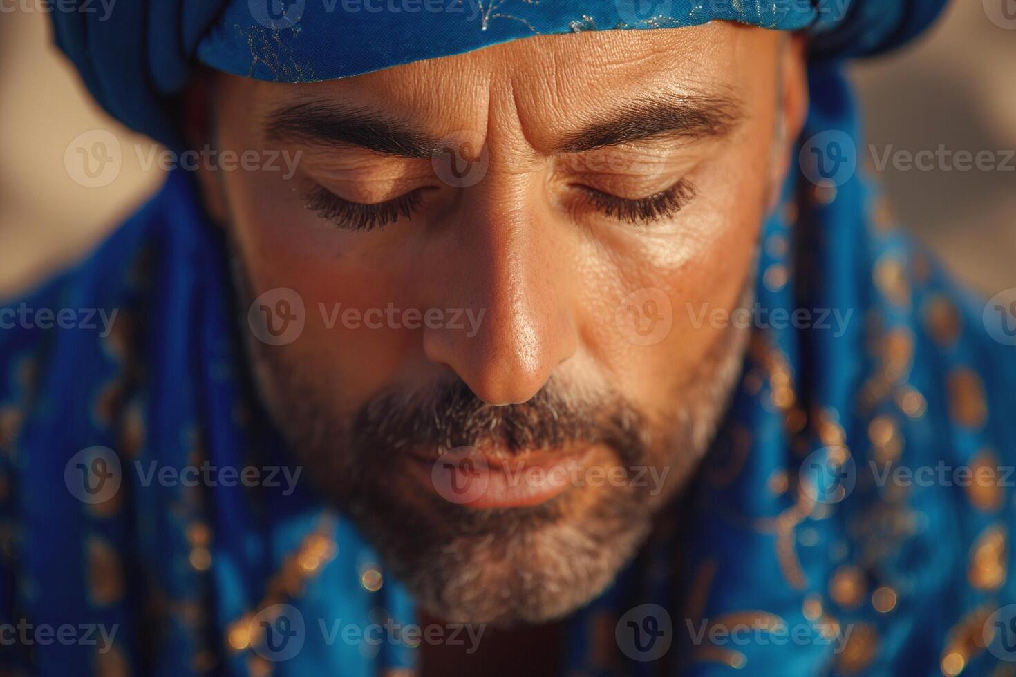 A contemplative Middle-Eastern man with a blue turban and scarf, showcasing deep thought and tranquility in a serene outdoor setting. photo