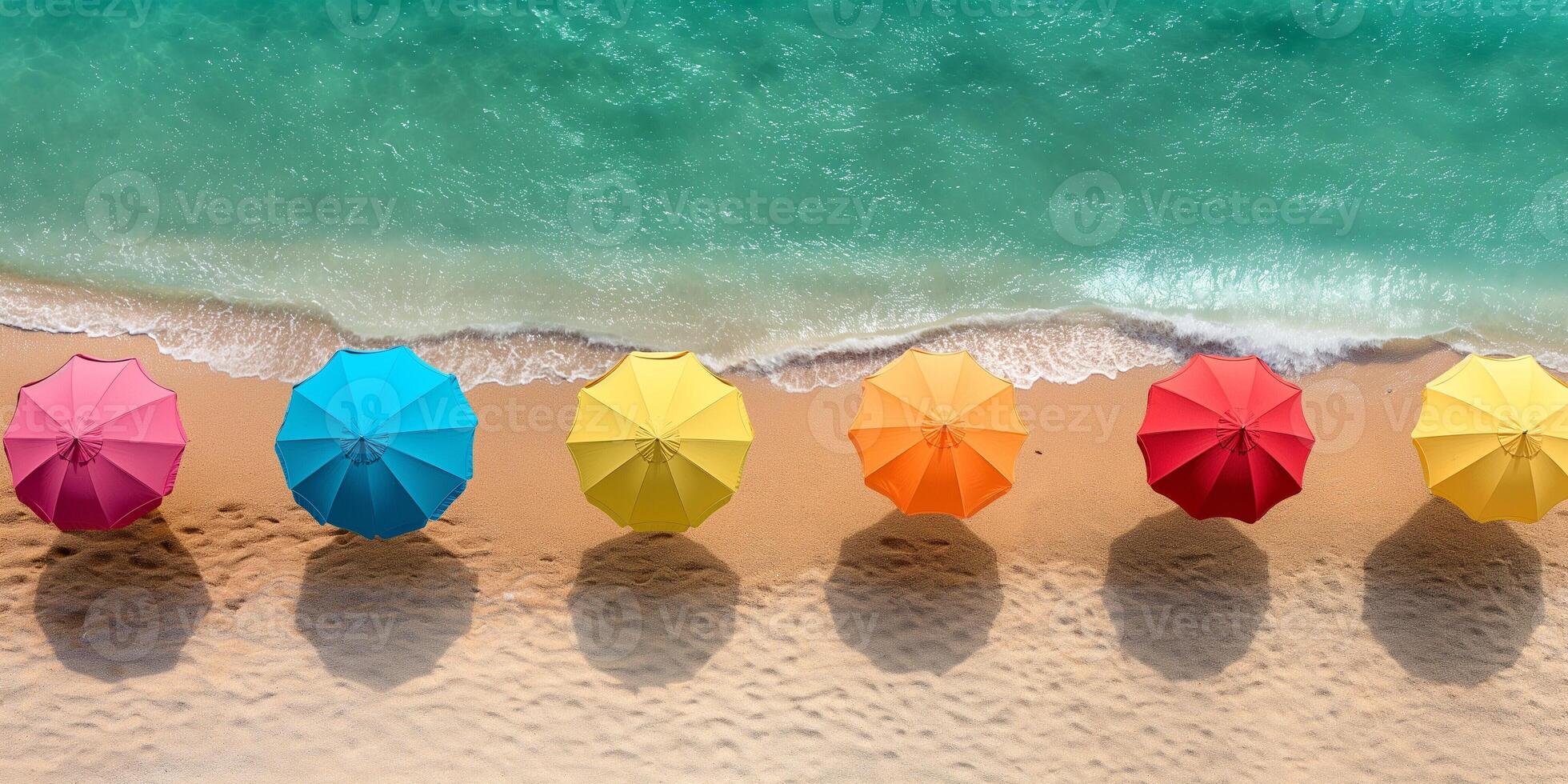Colorful beach umbrellas lined up on a sandy shore, casting shadows on the beach, creating a vibrant summer scene. photo