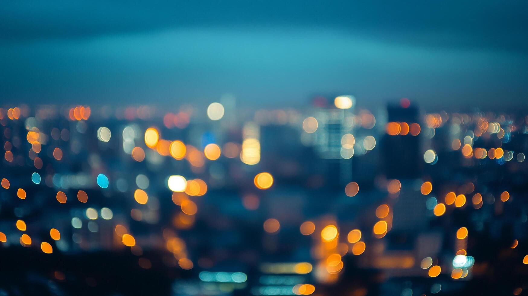 Out-of-focus city skyline at night, with bokeh lights creating a dreamy, abstract cityscape view under a dark blue sky. photo
