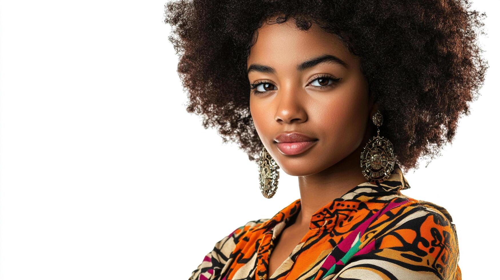 Portrait of a woman with an afro wearing patterned top and unique earrings against a bright white backdrop in a studio setting. photo