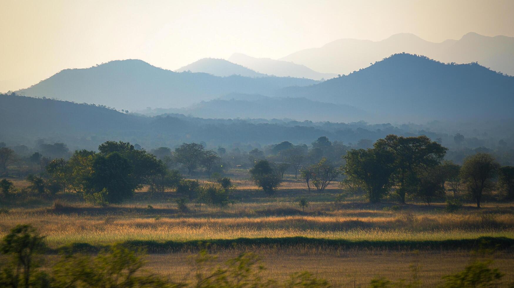 Serene landscape of mountains and grassland, bathed in soft light, evoking tranquility and natural beauty. Idyllic nature scene. photo