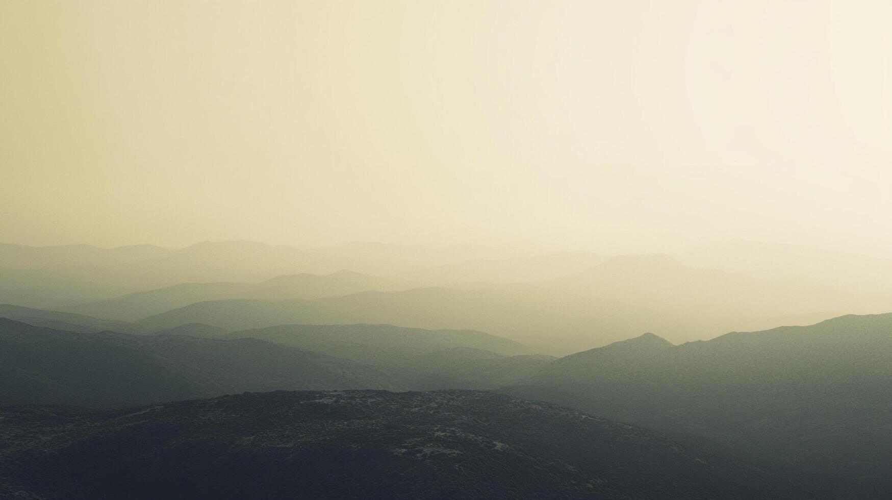 Layered mountain range receding into the horizon, with hazy light creating an ethereal landscape view, featuring peaks and valleys. photo