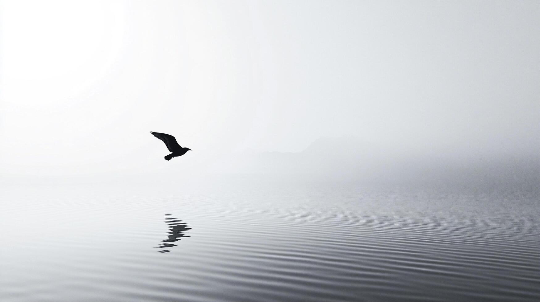A lone bird soars over calm water in a grayscale composition, with mountain silhouettes in the background and its reflection below. photo