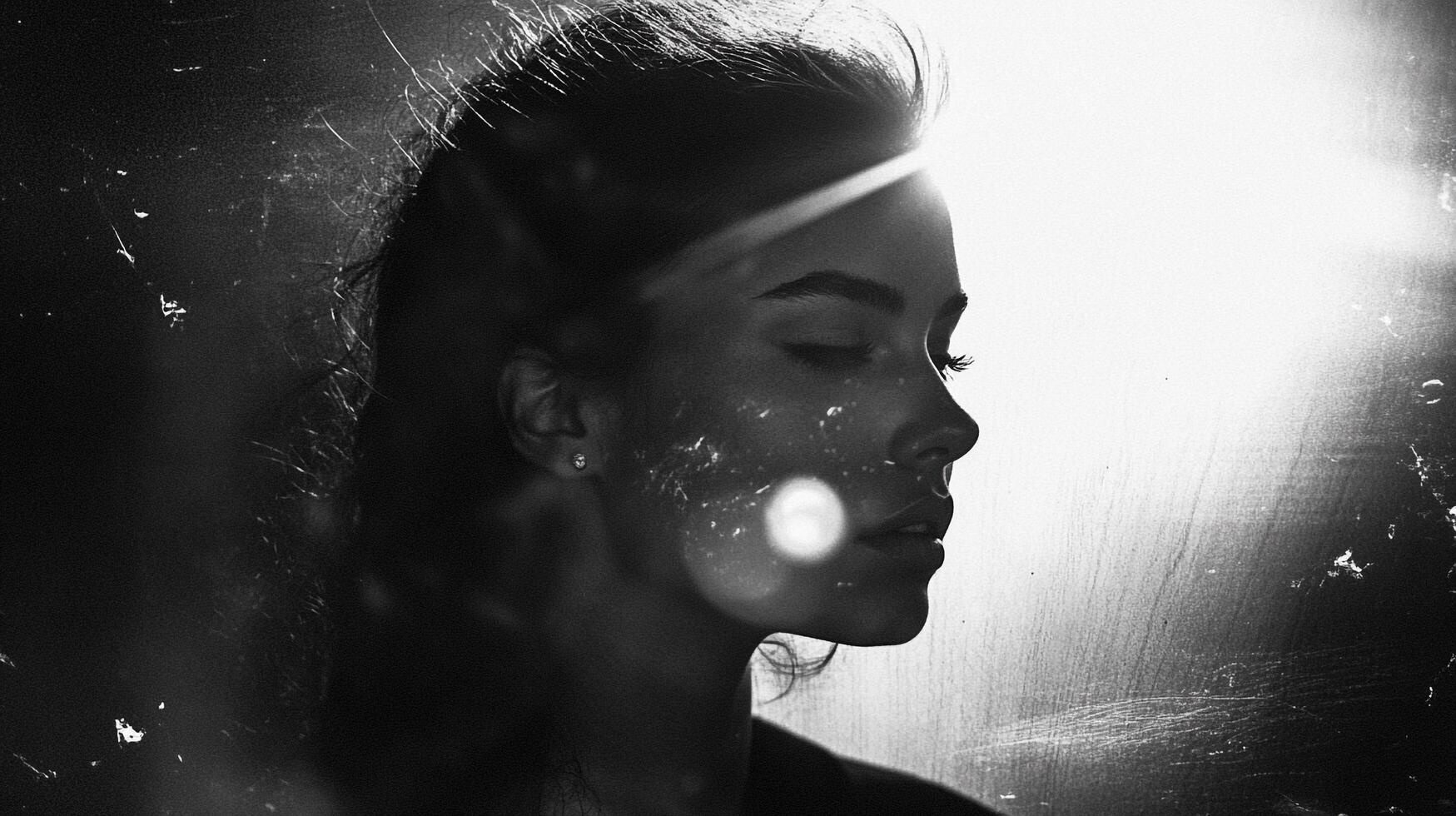 Monochromatic portrait of a woman in profile, eyes closed, with light flares and a gritty film effect for artistic emphasis. Serene and striking. photo