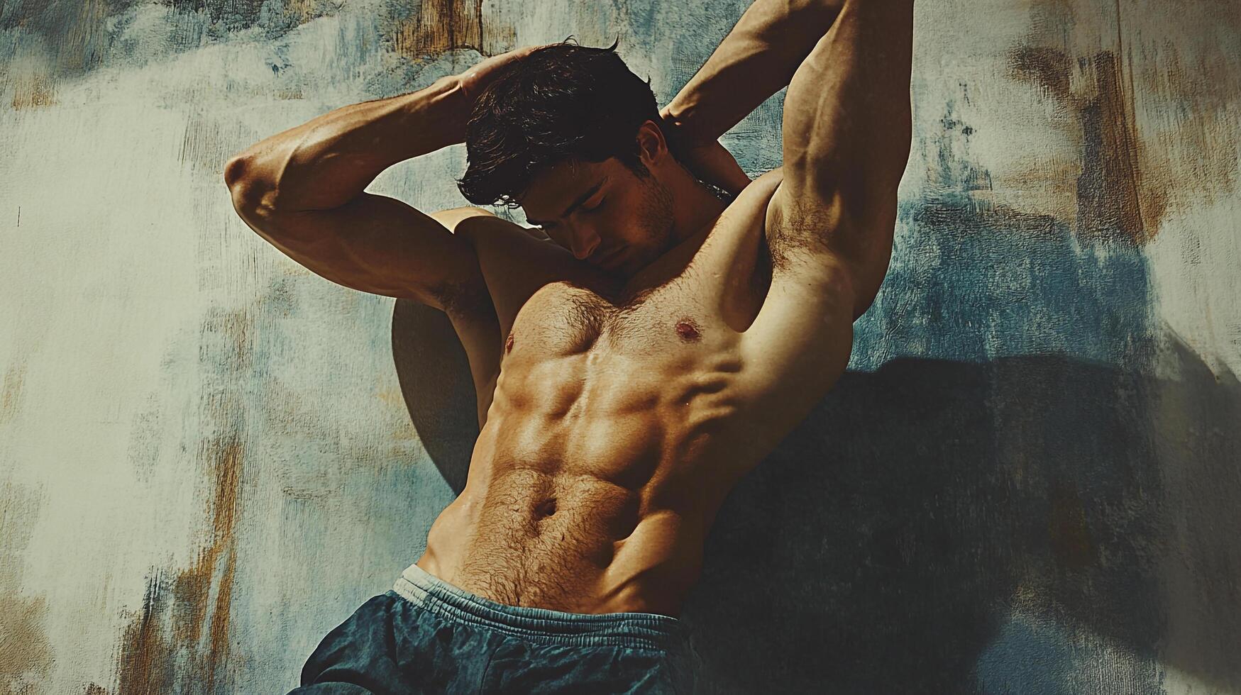 Athletic man showcasing sculpted physique, resting against textured wall, exuding strength and fitness, captured in a striking studio portrait. photo