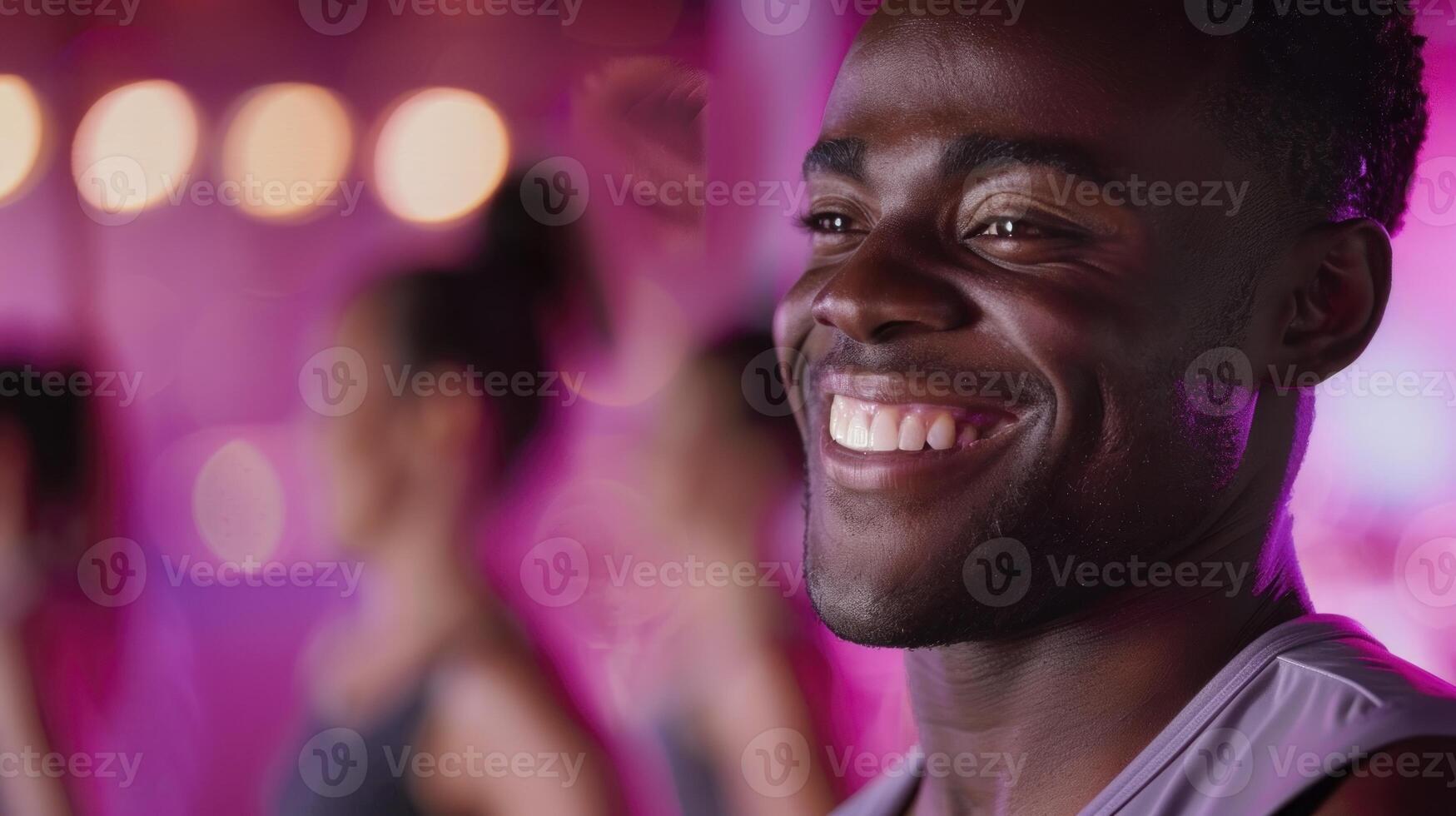 A man smiles while standing in front of a group of people photo
