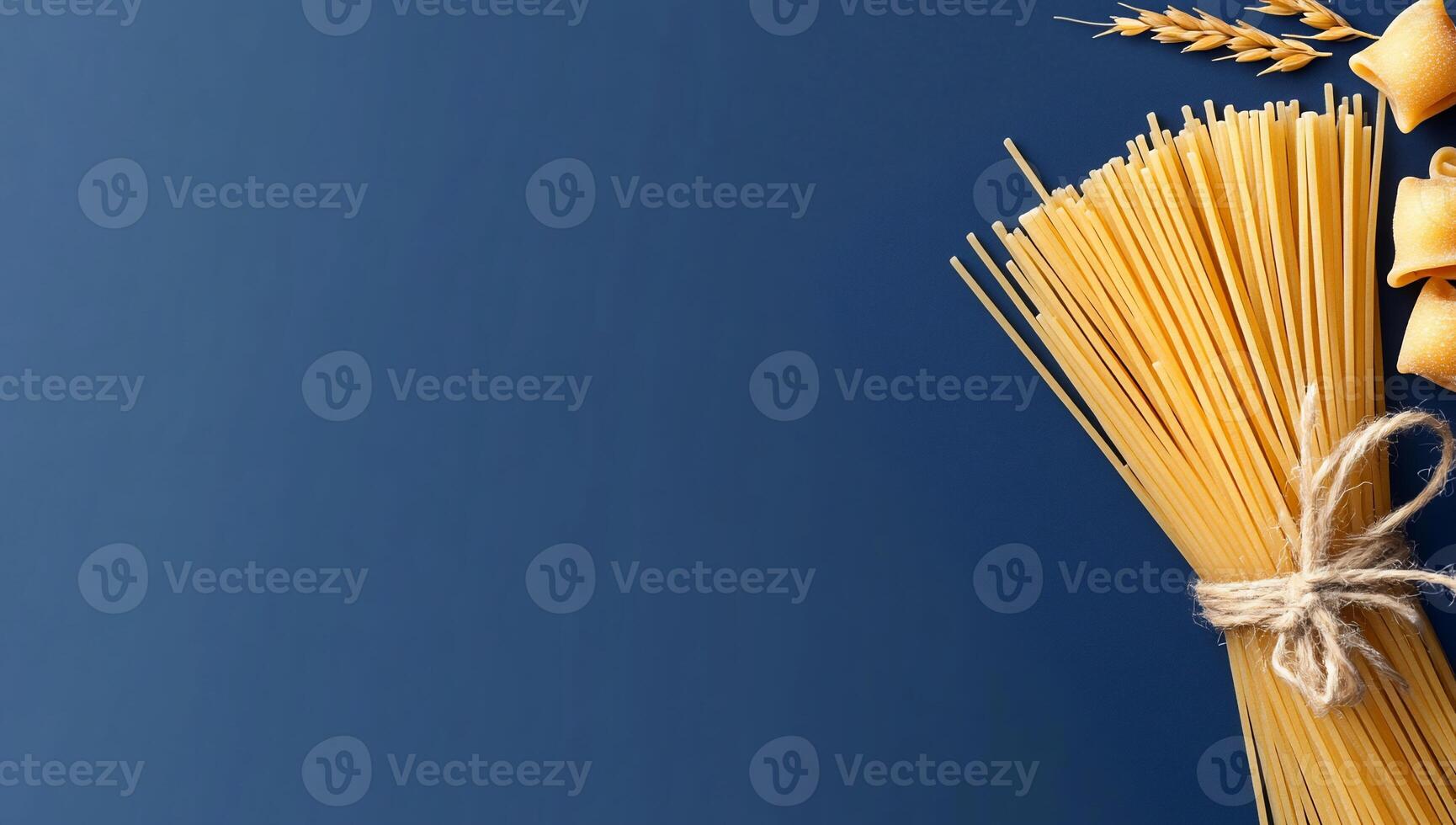A bundle of spaghetti and pasta shapes on a blue background. photo