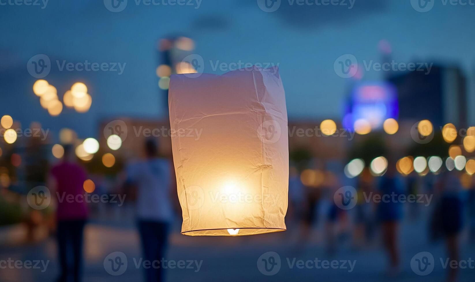 A glowing lantern floats above a bustling evening crowd. photo