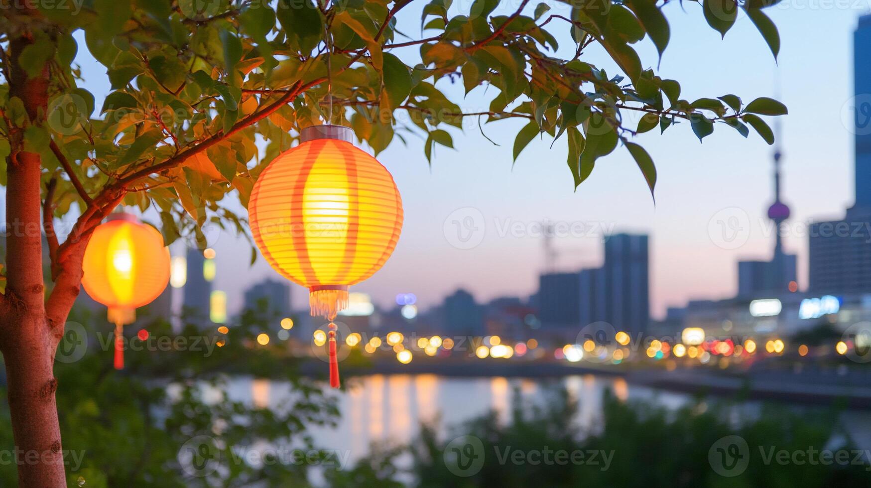 Lanterns hanging from a tree by a river at dusk in a cityscape. photo