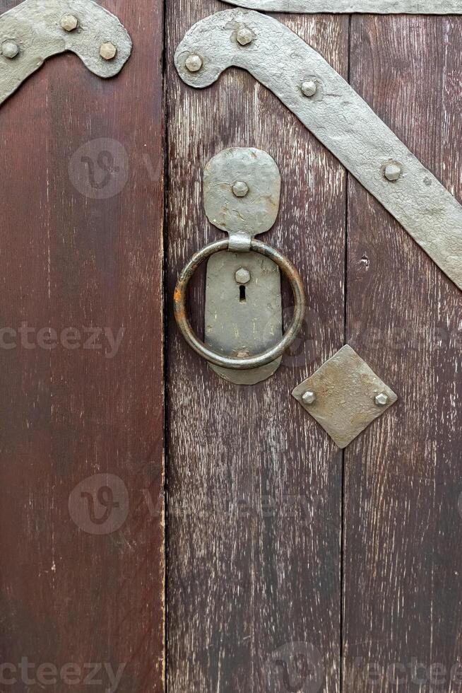 Rustic wooden door with metal hardware showcasing intricate details and traditional craftsmanship in an old building photo
