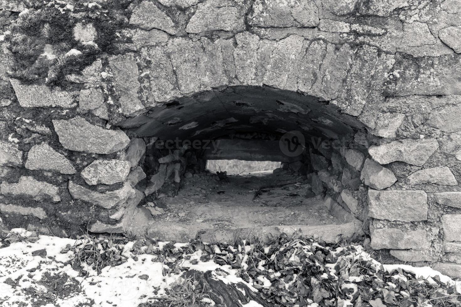 Stone archway reveals interior of historic structure nestled in snowy landscape during winter afternoon photo
