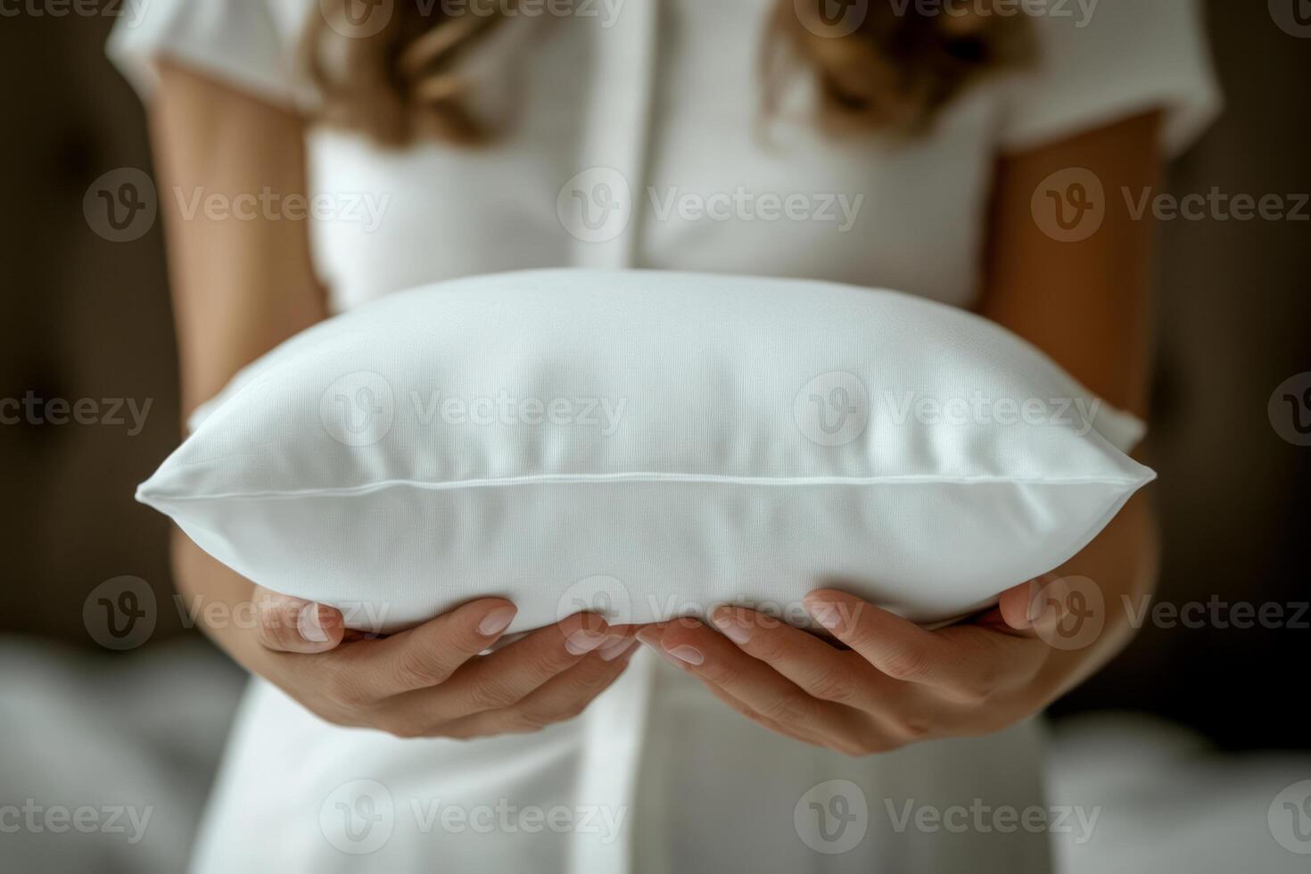 Woman holding soft white pillow in hands photo
