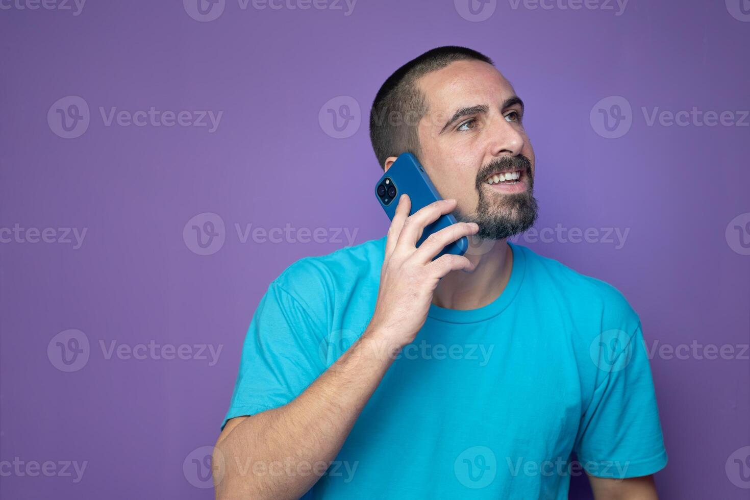 Happy young man talking with mobile phone on color background photo