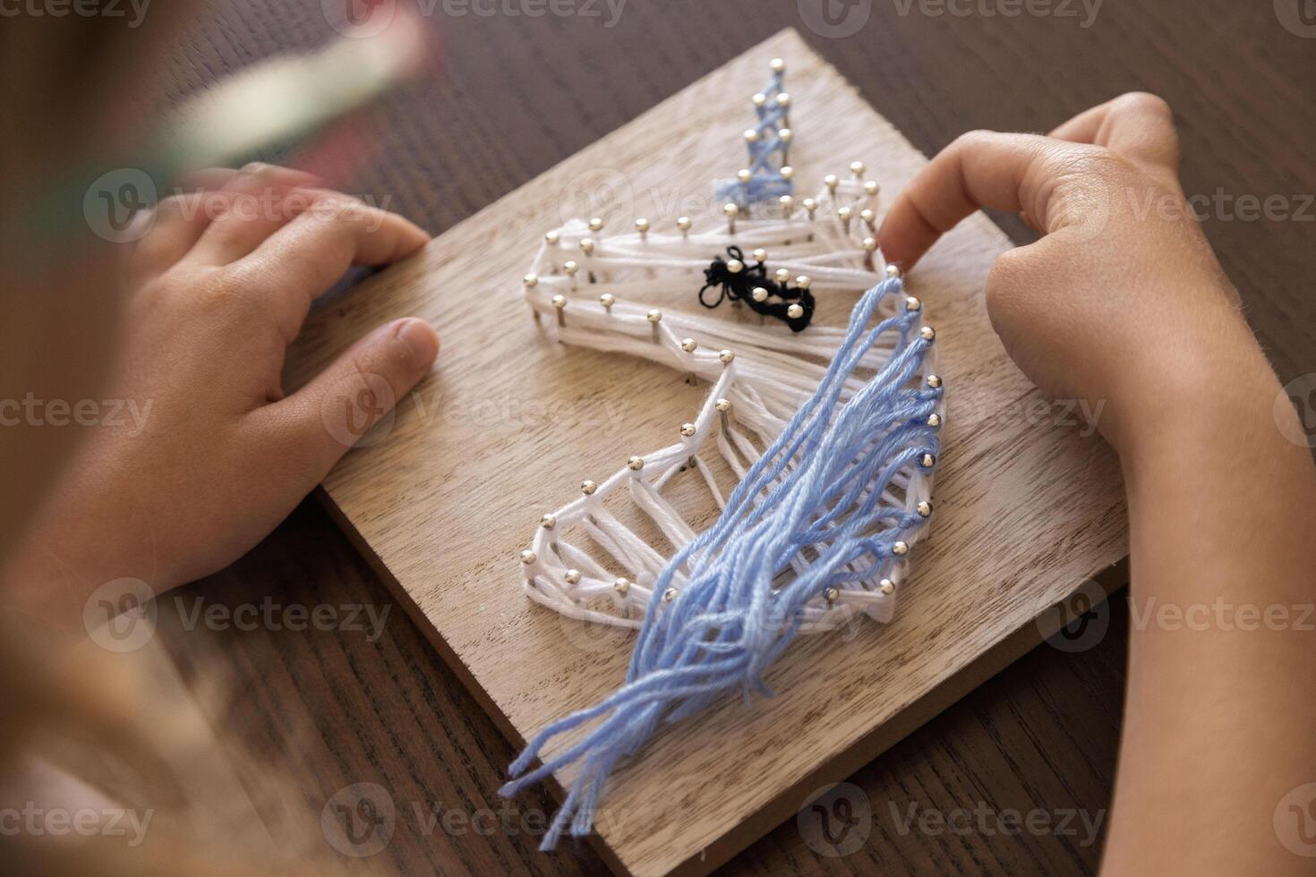Child creates intricate string art. Fostering focus, creativity, patience, and therapeutic skill development. photo