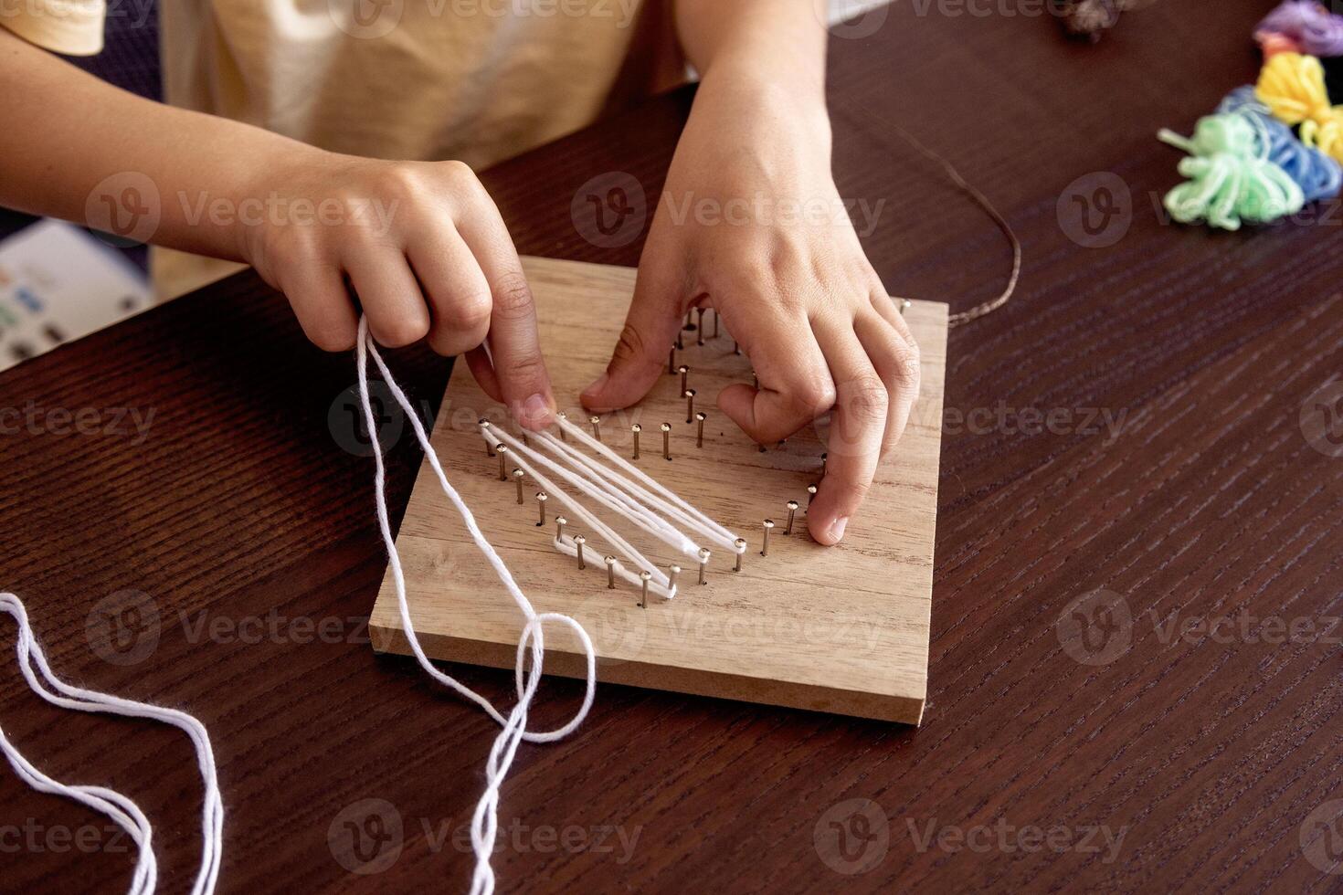 Little hands weave string around nails, crafting a beautiful design. A mix of patience, learning, and fun photo