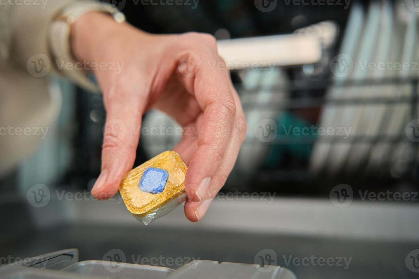 Close-up of female hand placing dishwasher detergent tablet into dispenser compartment. Efficient and hygienic dishwashing photo