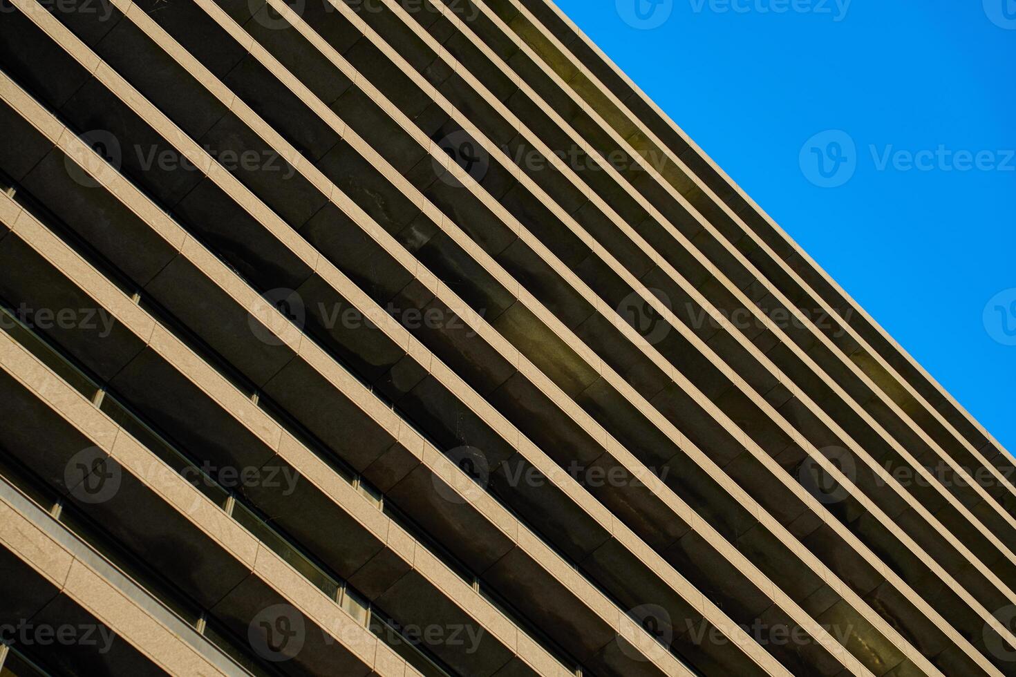 Contemporary architectural design with repeating geometric balconies against clear blue sky. Symmetry and minimalistic in modern urban building photo