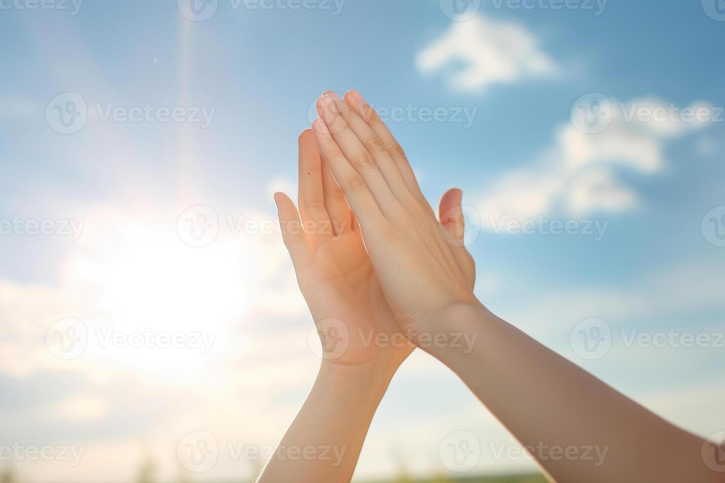 Hands raised against blue sky photo