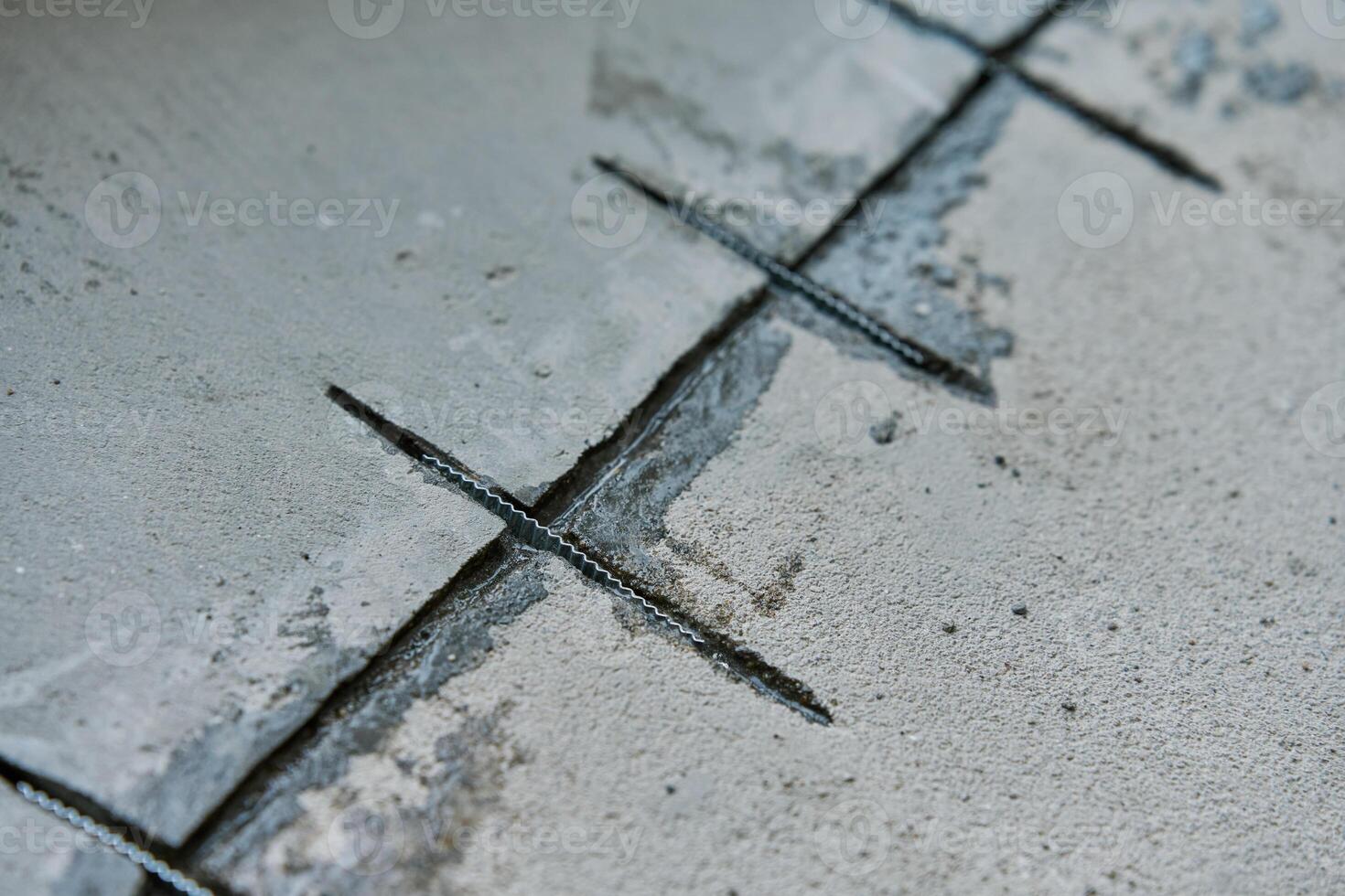 Close-up of concrete surface under repair with reinforcement bars inserted into cracks. Repairing cracks in concrete floor. Building renovation process photo