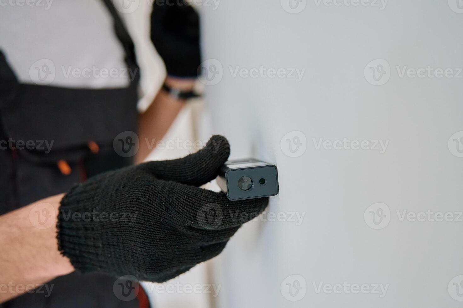 Worker using laser distance measurer on wall photo