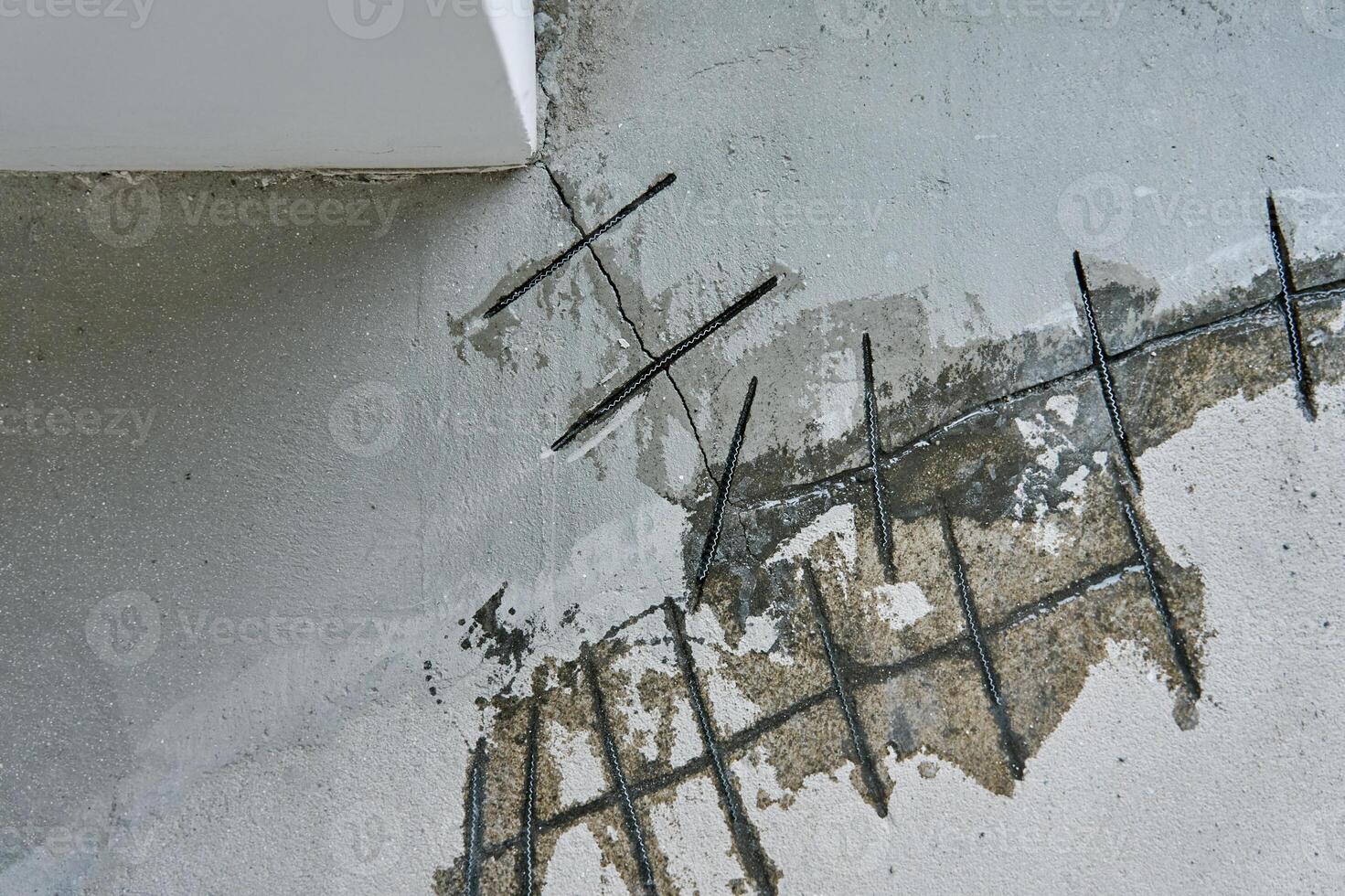 Close-up of concrete surface under repair with reinforcement bars inserted into cracks. Repairing cracks in concrete floor. Building renovation process photo