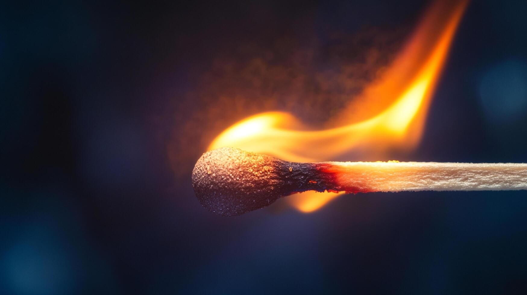 A close-up shot of a burning matchstick. The flame flickers intensely, illuminating the match head against a dark background. photo