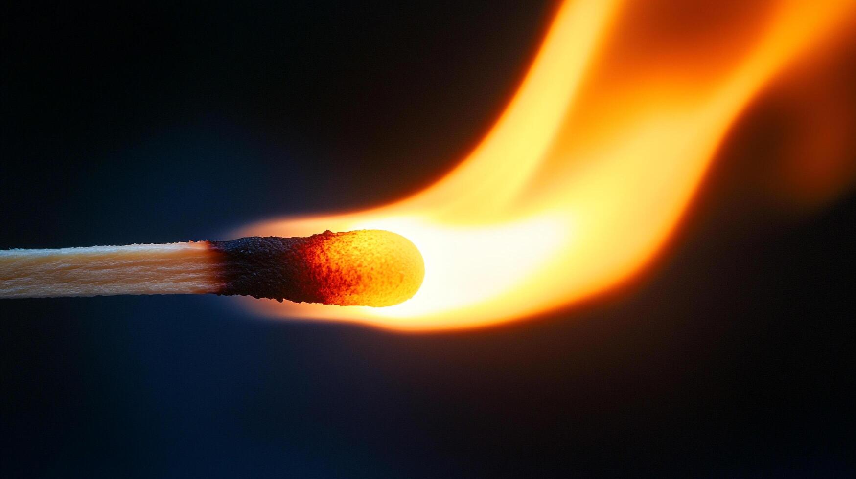 A wooden matchstick burns brightly against a dark backdrop, showcasing the start of a fire with its flame flickering upwards. photo