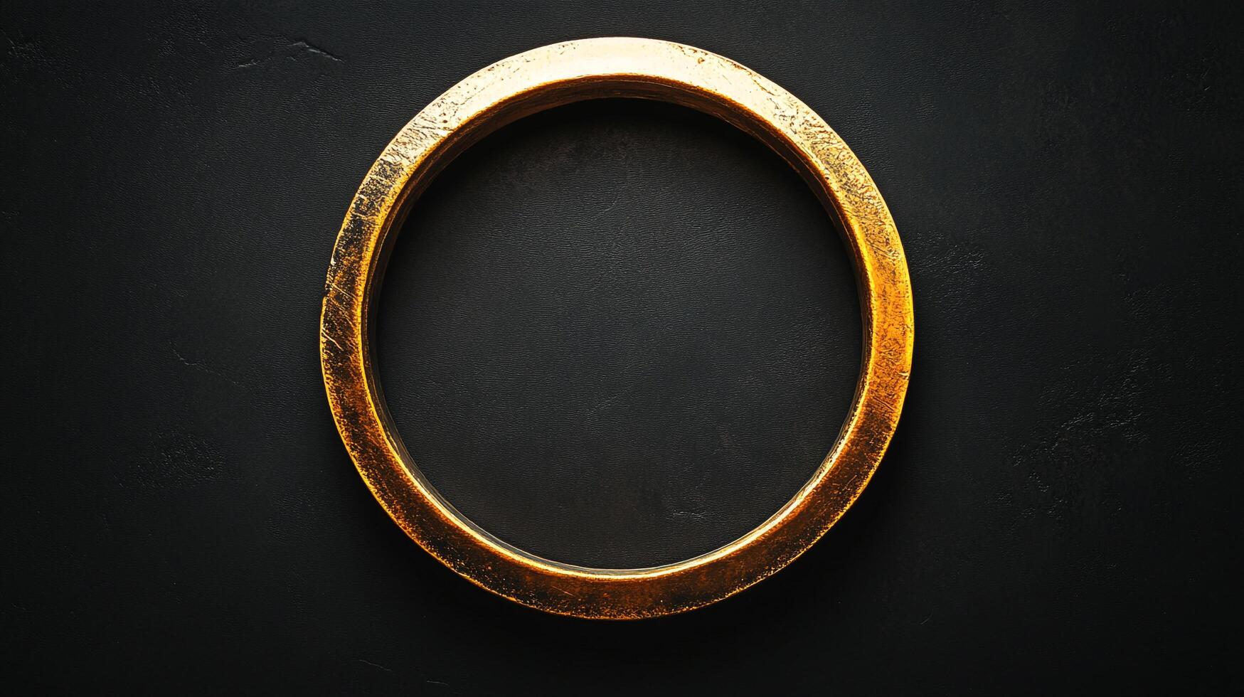 Golden circular ring on a black textured backdrop. The ring's aged texture contrasts with the smooth surface enhancing visual interest. photo