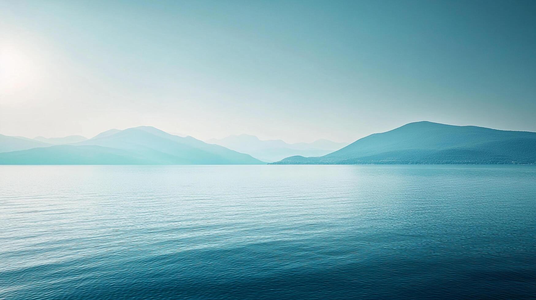 A serene water view showcasing muted tones of blue and green mountains reflecting in the calm water, creating a soothing and tranquil atmosphere. photo