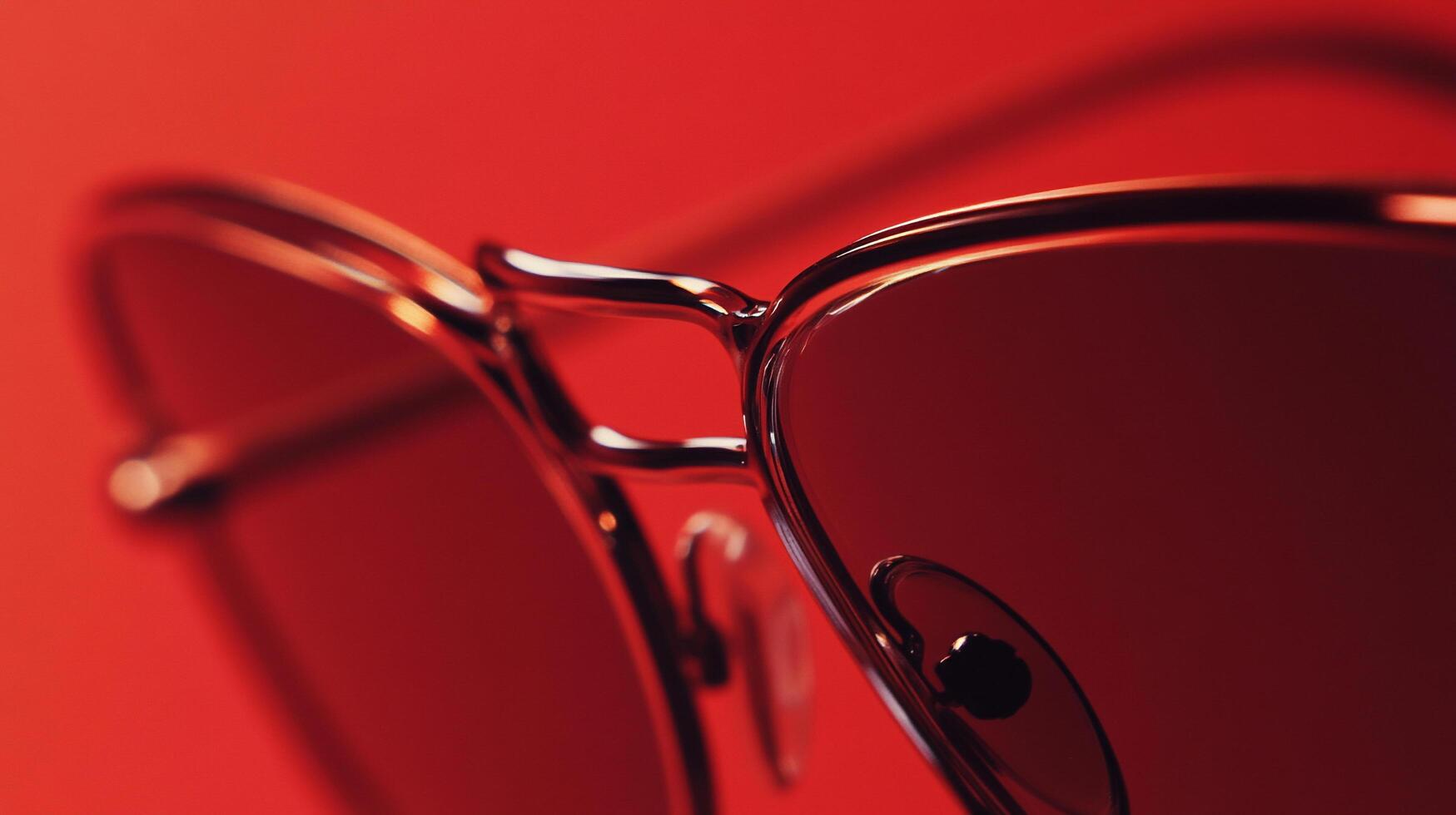 This striking image showcases a pair of stylish red sunglasses, reflecting light brilliantly, set against a vibrant backdrop that enhances the retro and fashionable elements of the design. photo