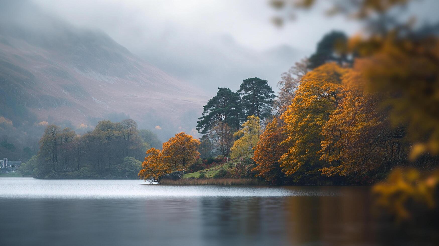 Lake shore in autumn, trees displaying vibrant fall colors against a backdrop of misty mountains and serene waterscape on a cloudy day. photo