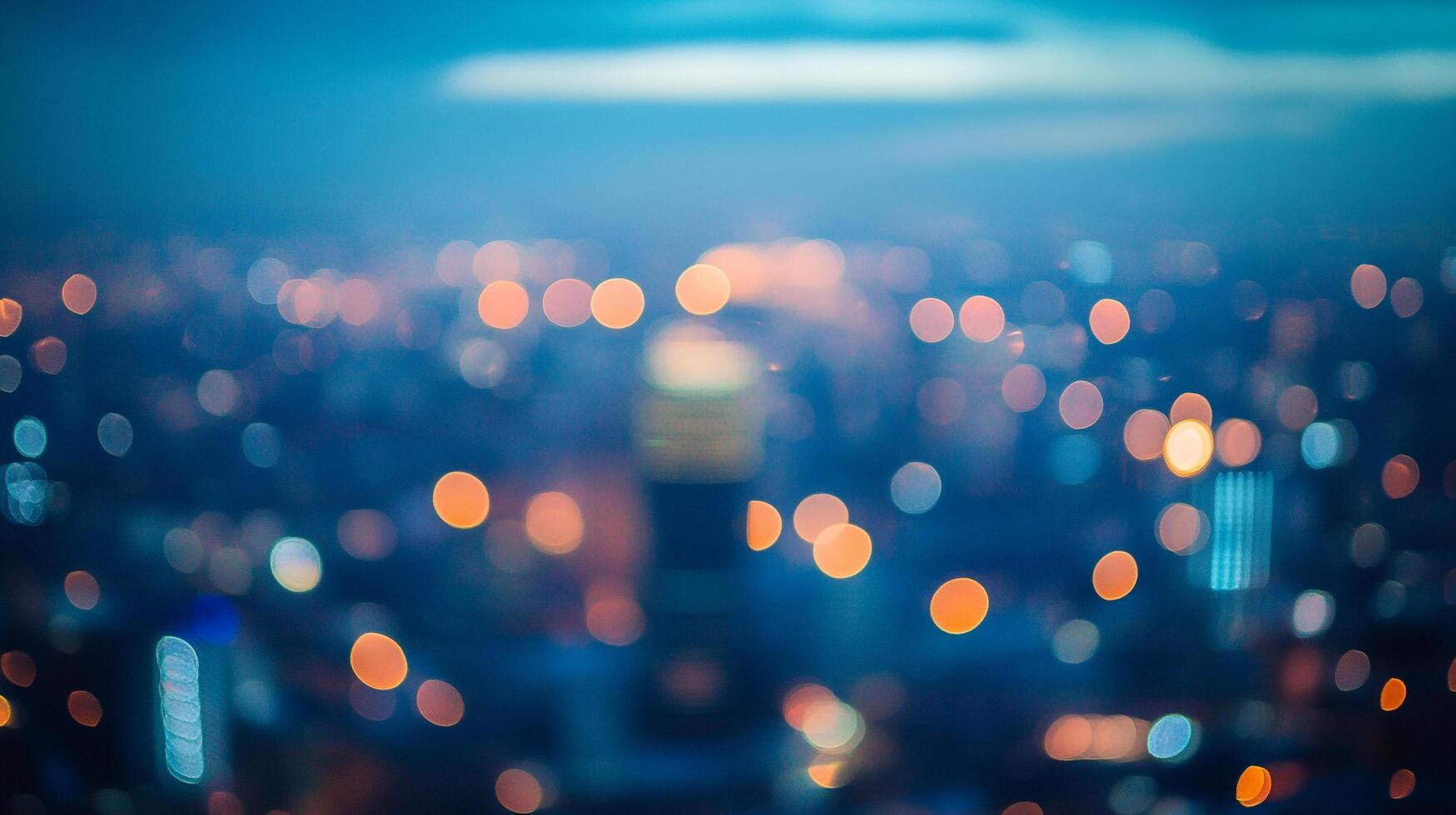 Blurred cityscape at twilight with bokeh lights creating a dreamy, abstract urban scene of a city at dusk from a high vantage point. photo