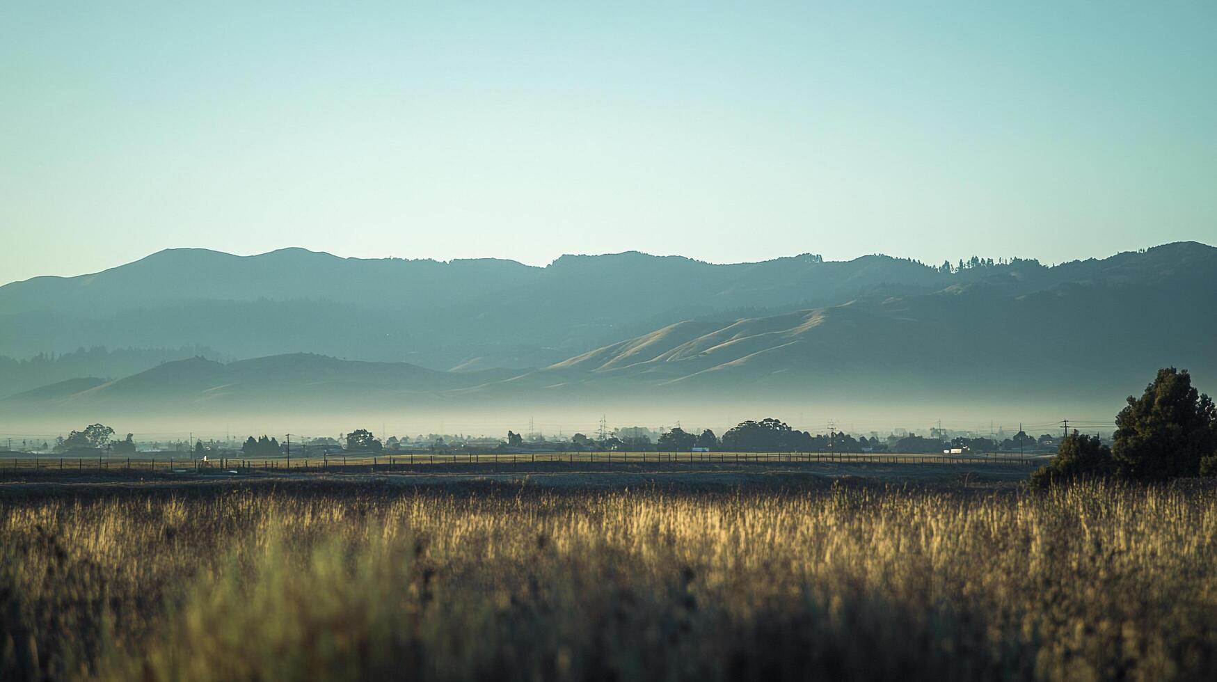 Misty mountain landscape with golden grass, presenting serene countryside with hills and trees. A calming vista with a peaceful ambiance. photo