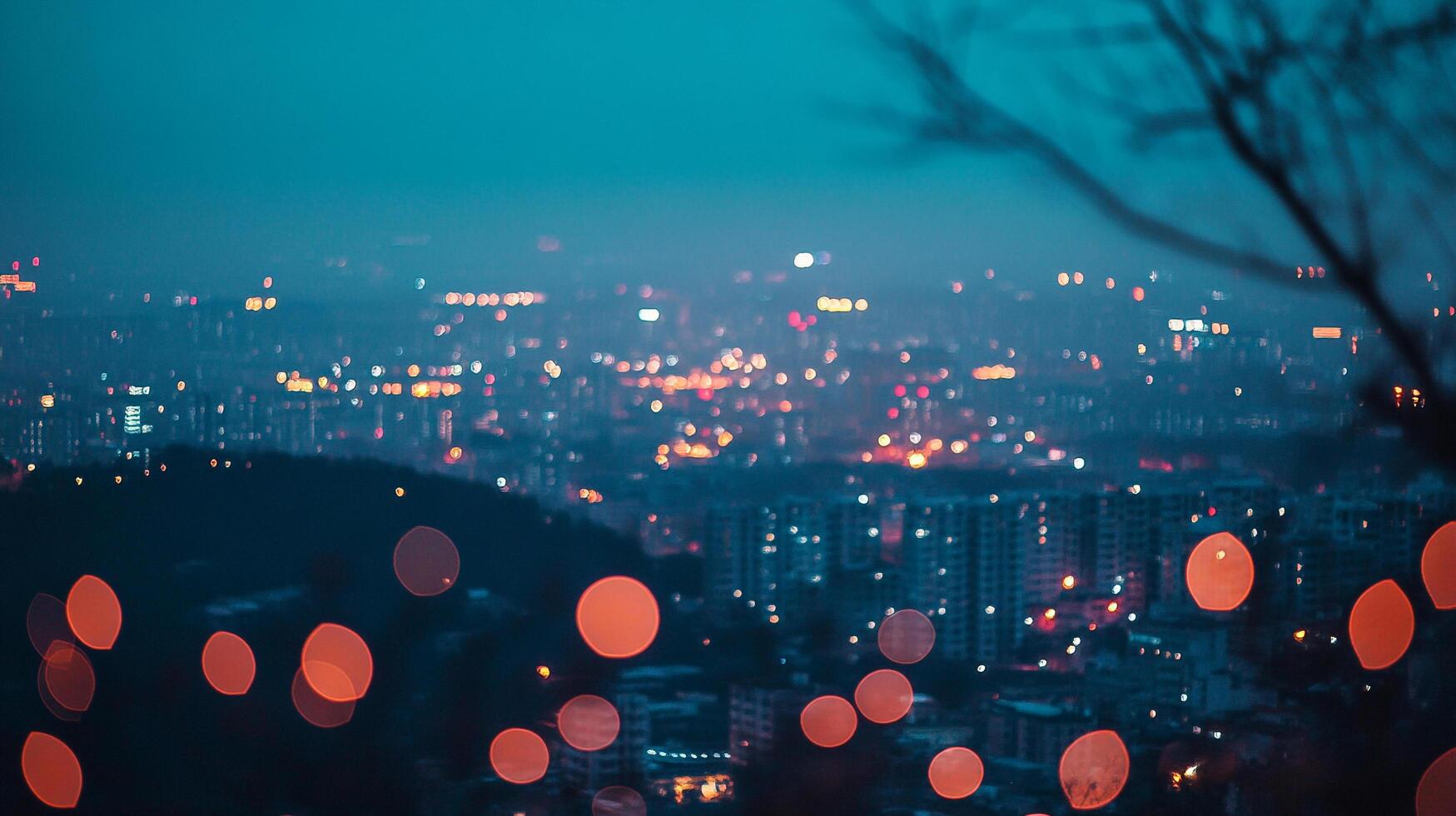 Night cityscape with blurred lights creating a dreamy bokeh effect against a dark blue sky, evoking a sense of urban beauty. photo