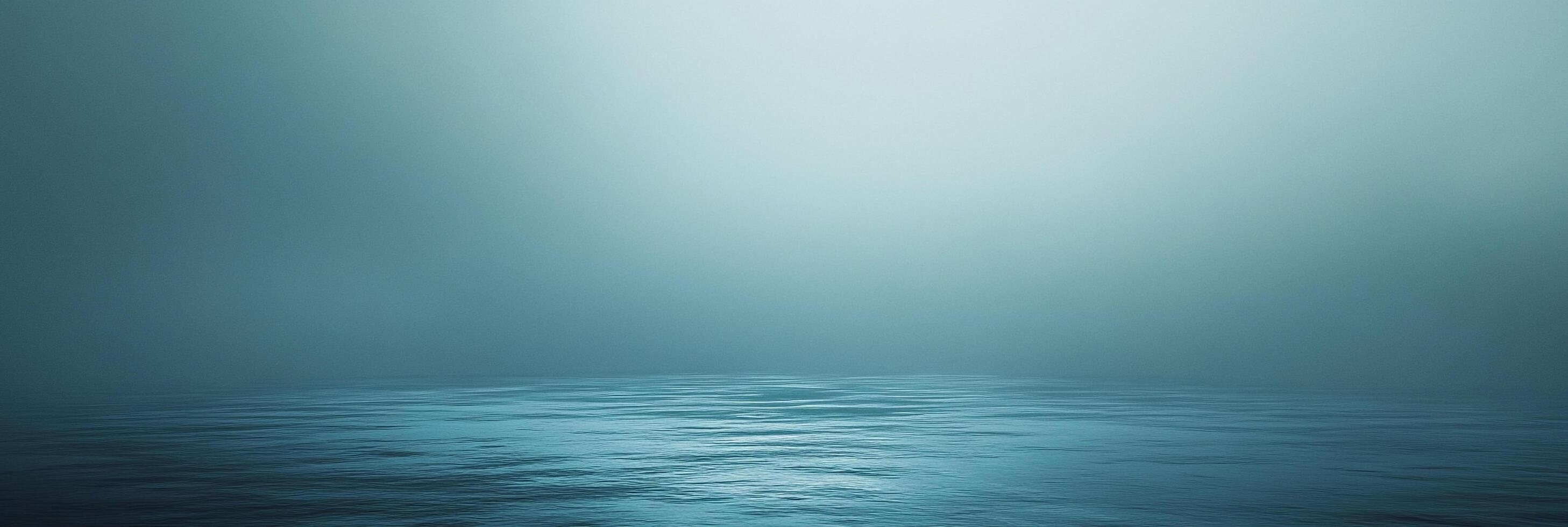 Tranquil water surface with a gradient light blue backdrop evoking serenity. Minimalist composition captures a sense of peace and depth. photo