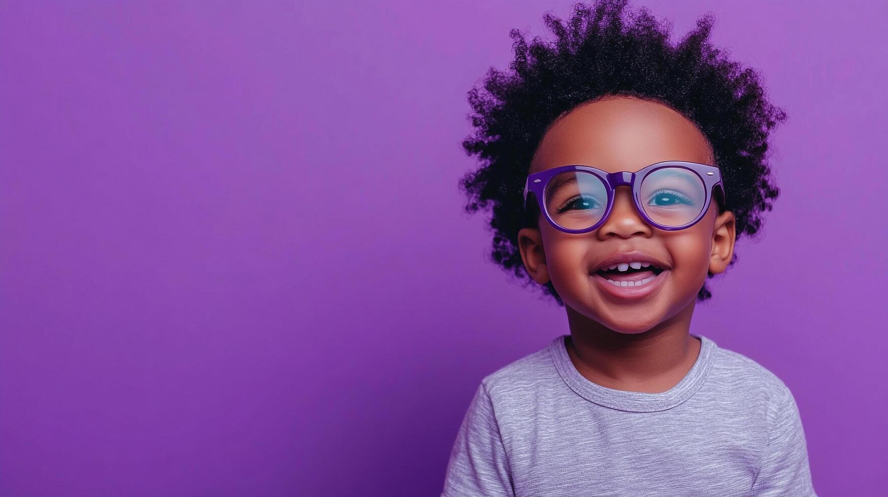 Adorable child with afro hair, wearing cute glasses and a shirt, laughing against a vibrant purple background. photo