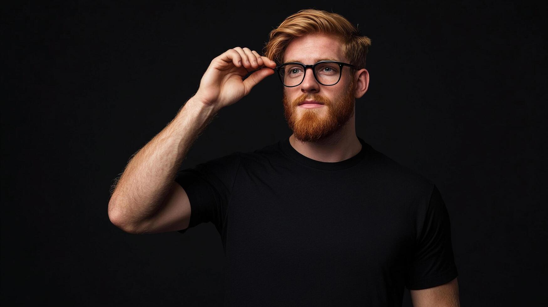 Portrait of a bearded man with red hair adjusting his glasses against a dark background, showcasing style and confidence. photo